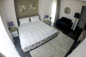 Ein Schlafzimmer im Demi Hotel mit einem großen Bett, weißen Decken, Kissen und einem weißen Teppich.