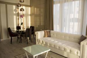 Wohnbereich im Demi Hotel mit weißem Sofa, Glastisch und Esstisch mit Blumenvase