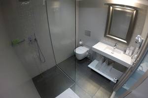 Badezimmer des Demi Hotel mit Dusche, Toilette, Waschbecken und Handtuchtrockner.