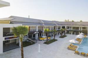 Außenansicht des Emotions By Hodelpa Puerto Plata Hotels mit gelbem Auto und Sonnenliegen