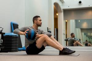 Ein Mann trainiert in einem Fitnessstudio mit einem Medizinball.
