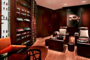Salonbereich im Grand Hyatt Dubai mit Ledersesseln, Nagellackregalen und einer großen Frau auf der Wand.