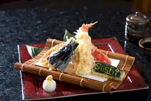 Ein Sushi-Teller mit verschiedenen Sushi-Stücken und einem Schriftzug, der Sushi auf dem Teller sagt.