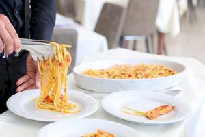 Ein Kellner serviert Spaghetti mit Garnelen im Dyrrah Hotel.