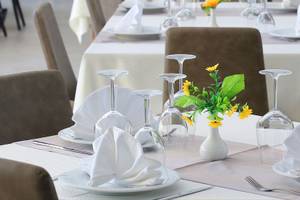 Ein Tisch im Dyrrah Hotel ist gedeckt mit Tellern, Gläsern und einem Blumenstrauß in einer Vase.