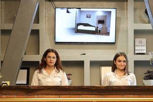 Zwei Frauen an der Rezeption des Dyrrah Hotels, davor eine Anzeige auf einem Monitor.