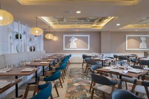 Innenansicht des Restaurants Emotions By Hodelpa Puerto Plata mit blauen Stühlen und Tischen.