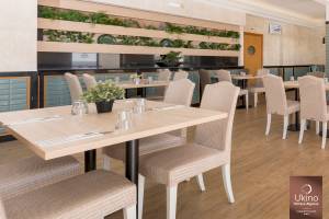 Innenbereich des Restaurants im Ukino Terrace Algarve Hotel mit Tisch und Stühlen, grünen Pflanzen und Holzboden.