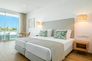 Ein Hotelzimmer mit zwei Betten, Blick auf den Pool, modernes Design und heller Einrichtung.