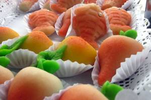 Nahaufnahme von verschiedenen fisch- und aprikosenförmigen kuchen in weißen papierförmchen