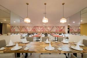 Innenansicht des Restaurants im Emotions By Hodelpa Hotel in Puerto Plata, mit gedeckten Tischen und stilvollen Wanddekorationen.