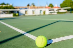 Tennisball auf einem Tennisplatz im Schatten des Netzes