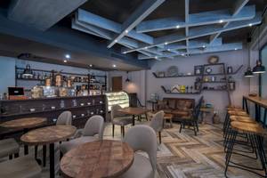 Innenbereich des Emotions By Hodelpa Puerto Plata Hotels mit Holztischen, Stühlen und einer Bar.