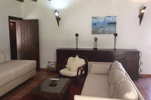 Wohnzimmer des Pedras da Rainha Resorts mit zwei Sofas, einem Tisch und einem Gemälde an der Wand.