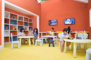 Kinder spielen in einem farbenfrohen Zimmer mit Tischen und Stühlen.