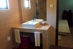 Ein Badezimmer mit einem Waschbecken, Spiegel und einem Bett im Hintergrund.