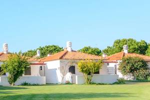 Außenansicht des Pedras da Rainha Resorts mit weißen Gebäuden und roten Dächern auf einem grünen Rasen