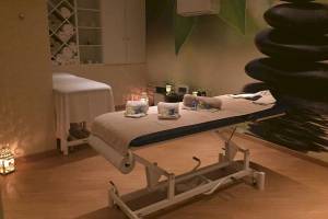 Massageraum im Baia Grande Hotel mit Behandlungstisch, Liegen und steinigen Dekoration.