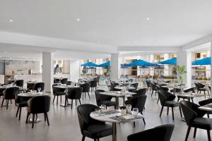 Innenansicht des Restaurants im Pickalbatros Blu Spa Resort mit blauen Sonnenschirmen und Tischen.