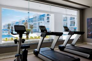 Fitnessstudio mit drei Laufbändern und Ausblick auf einen Pool im Pickalbatros Blu Spa Resort.