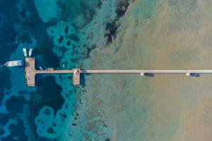 Luftaufnahme des Amwaj Beach Clubs mit Pier im Wasser und mehreren Booten