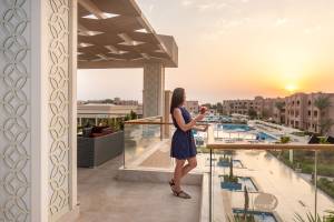 Frau auf dem Balkon des Pickalbatros Aqua Vista Resorts mit Blick auf den Pool bei Sonnenuntergang.