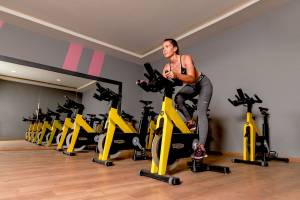 Eine Frau trainiert auf einem Spinnrad in einem Fitnessstudio, umgeben von weiteren Spinnrädern.