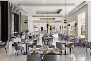 Innenansicht des Restaurants im Pickalbatros Aqua Vista Resort mit runden Tischen, Stühlen und Speisentellern.