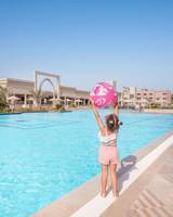 Ein junges Mädchen am Rand des Swimmingpools des Pickalbatros Aqua Vista Resorts, das einen rosa Ball hochhält