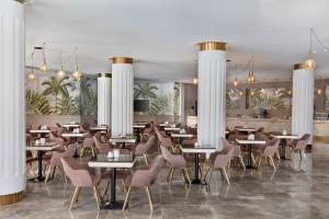 Innenansicht des Restaurants im Pickalbatros Water Valley Resort by Neverland mit runden Tischen, Stühlen und Säulen.