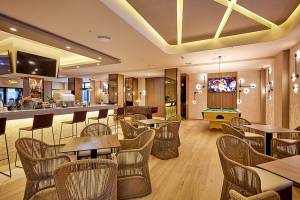 Innenansicht der Bar im RIU Palace Macao Hotel mit Barhockern, Tischen und Fernsehern.