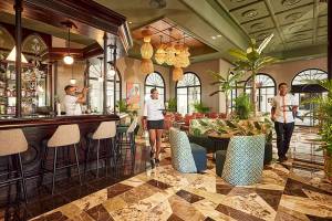 Lobby des RIU Palace Macao Hotels mit Bar, Gästen und tropischen Pflanzen.