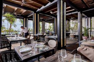 Das RIU Palace Macao Innenrestaurant mit Tischen, Stühlen und einem Kellner, der die Tische einrichtet.