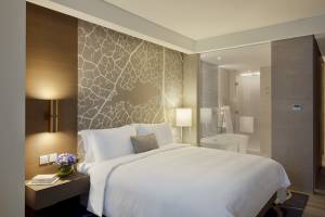 Schlafzimmer im Al Bandar Rotana mit Bett, Nachttisch, Lampen und Badezimmer mit Badewanne