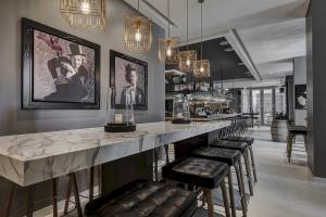 Sitzecke in der Bar des Al Bandar Rotana Hotels mit Marmortisch und schwarzen Lederstühlen.