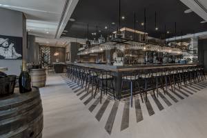 Innenansicht der Bar im Al Bandar Rotana Hotel mit geometrischen Bodenfliesen und einer langen Bartheke.