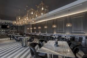 Innenansicht des Al Bandar Rotana Hotel Restaurants mit modernen Möbeln und goldenen Kronleuchtern.