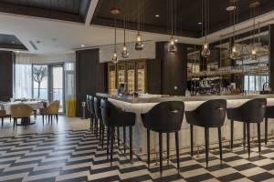 Innenansicht der Bar im Al Bandar Rotana Hotel mit schwarzen und weißen Sesselreihen und Marmortheke.