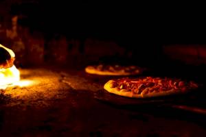 Pizza im Ofen beim Backen mit offenem Feuer
