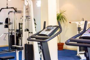 Fitnessstudio im Golden Beach Resort mit Laufband und Hanteln neben einer Zimmerpflanze