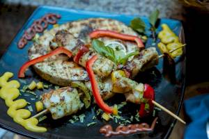 Gegrillter Fisch mit Gewürzen und Gemüse auf einem blauen Teller.