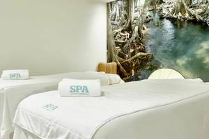 Spa-Behandlungszimmer im Iberostar Cristina Hotel mit weißen Handtüchern und einem Panoramabild an der Wand.