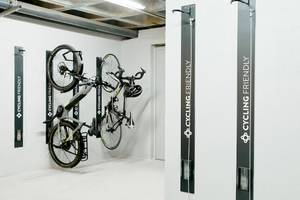 Fahrräder, die an der Wand eines Hotels aufgehängt sind, mit Schildern, die 'Cycling Friendly' und 'Cycling' bedeuten.