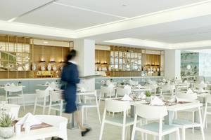 Innenansicht des Restaurants im Iberostar Cristina Hotel mit modernen weißen Tischen und Stühlen.