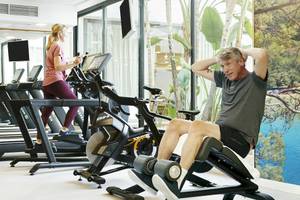 Fitnessstudio im Hotel Iberostar Cristina mit mehreren Personen, die auf Laufbändern und Fahrrädern trainieren.