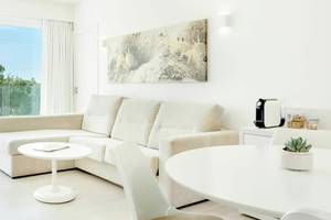 Wohnzimmer im Iberostar Cristina Hotel mit Sofa, Tisch und Aussicht auf den Garten.
