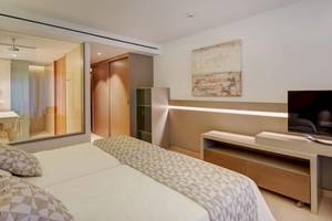 Schlafzimmer im Hipotels Gran Playa de Palma Hotel mit zwei Betten, Fernseher und Glaswand.