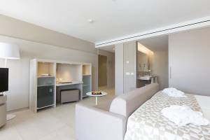 Innenansicht der Suite im Hipotels Gran Playa de Palma mit Bett, Sofa, Schreibtisch und Bad.