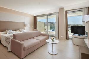 Modernes Hotelzimmer mit einem Sofa, einem Bett, einem Tisch und einem Fernseher auf einem Balkon.