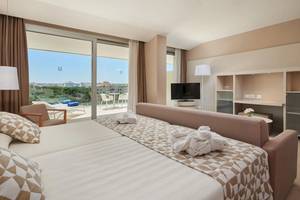 Innenansicht eines Zimmers im Hipotels Gran Playa de Palma mit großem Bett und Balkon.